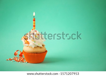 Delicious birthday cupcake with candle on light green background. Space for text