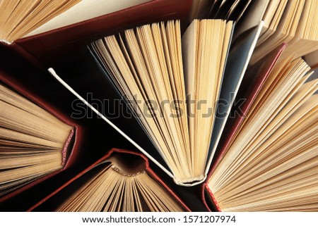 Many different hardcover books on dark background, top view