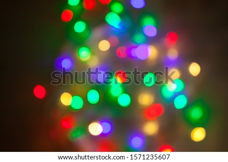 Abstract Christmas background. Photo of glowing blurry lights. Decoration garland with multi-colored flickering lights.
