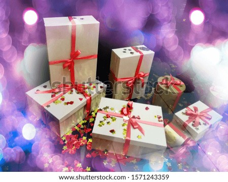 boxes with Christmas gifts tied with red ribbon on a dark background, around the bokeh blurred festive for postcards. the image has noises and artifacts.