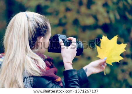 A woman with camera in the autumnal park