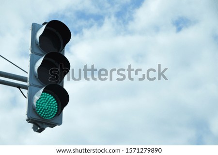 Traffic signal with sky and clouds background.