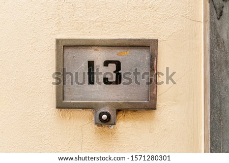 An old ruined doorbell with a "13" on it. Royalty-Free Stock Photo #1571280301