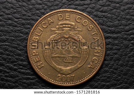 Costa Rican coins on black leather