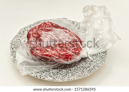 Frozen raw hamburger meat waiting to be defrosted. Royalty-Free Stock Photo #1571286595