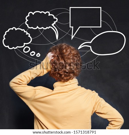Thinking child looking at empty speech clouds bubbles on chalkboard background