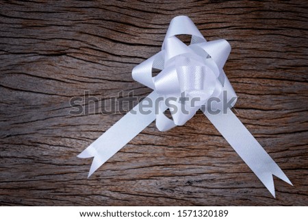 White ribbon bow on wooden backgound.