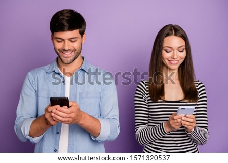 Photo of two people couple guy lady holding telephones counting likes followers reposts shares addicted social network users wear casual outfit isolated purple color background