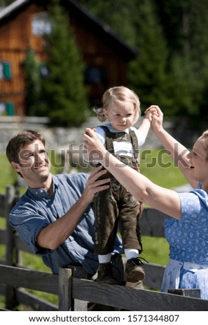 Young family in Austria countryside, girl walking on fence