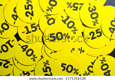 Yellow round stickers with discounts of 10 to 50 percent. Sell-out. Discounts on a black background. Black Friday. Price fall. Posters. Macro discounts Royalty-Free Stock Photo #1571356528