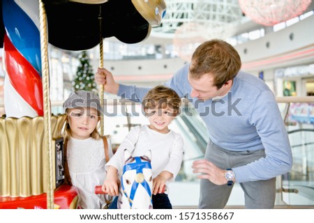 Father and children at carousel in shopping mall