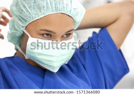 Teenage girl putting on surgical mask in operating room