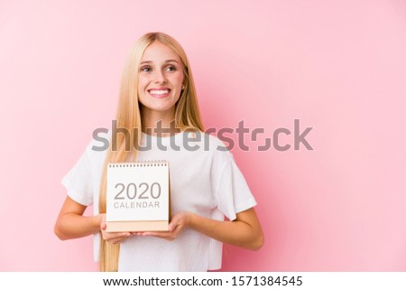 Young girl holding a 2020 calendar smiling confident with crossed arms.