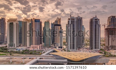 Aerial view to Sheikh Zayed road during sunrise from Dubai Marina with JLT skyscrapers timelapse, Dubai. Traffic and metro station. Orange cloudy sky. United Arab Emirates