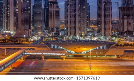 Aerial view to Sheikh Zayed road from Dubai Marina with JLT illuminated skyscrapers night to day transition timelapse, Dubai. Traffic, footbridge and metro station. United Arab Emirates