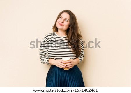 Young curvy woman holding a coffee dreaming of achieving goals and purposes