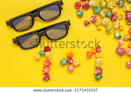 Popcorn and 3d glasses on yellow background. Concept of cheap movie tickets, bring a friend, 1 ticket free for 3D cinema.