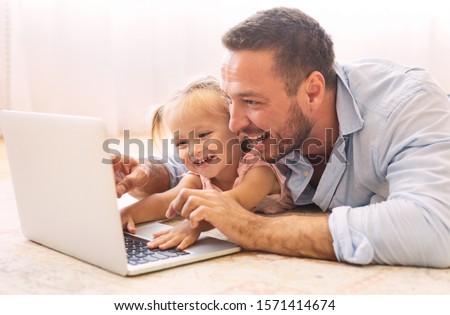 Family Time. Father and daughter making video call to mother using laptop on the floor. Copy space