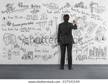 Businessman writing about home sales on a wall in white room 4
