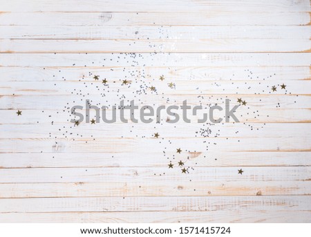 Christmas background card ornate with golden star sparkles on white bleached wooden planks. Winter time top view