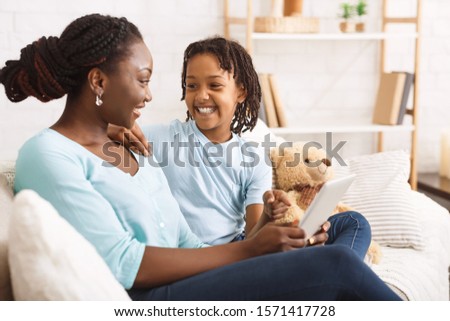 African American Mom Showing Daughter Her Photos On Digital Tablet. Copy space