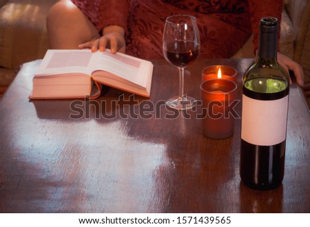 Beautiful composition with glass of wine with old books with candles on table close up,red wine bottle without label