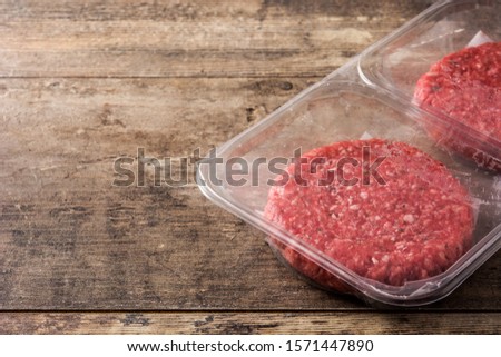 burger meat packaged in plastic on wooden table. Copy space