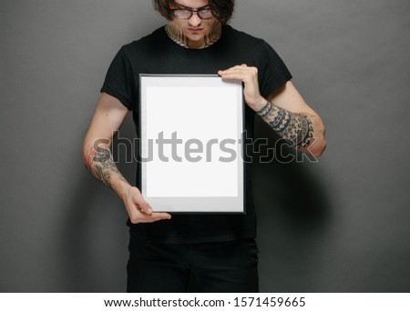 Man holding a picture frame or poster for mock up wearing black clothes
