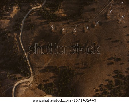 Aerial drone panorama shot of high mountain area, windmills, the long and winding road through the mountains. Southern region, sands, desert, birds eye view, sea shore on the background