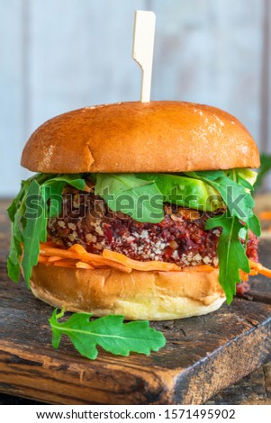Homemade vegetarian beetroot burger with avocado, rocket lettuce and carrot slaw in brioche bun