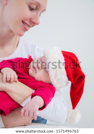 Mother holding  her baby daughter in Santa hat