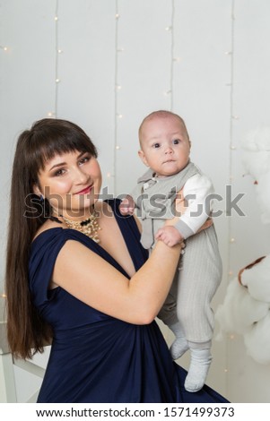Happy mother in evening dress with a child in a photo studio.