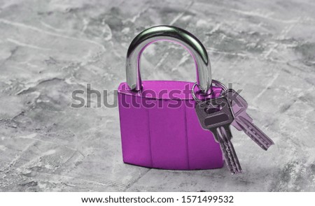 Metal lock with keys on gray concrete background.