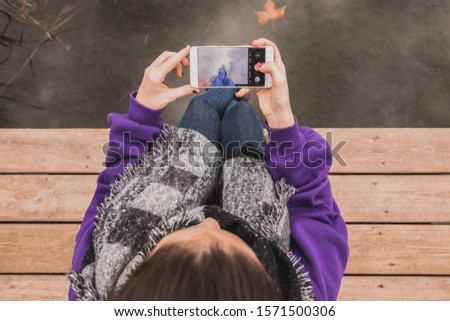girl sitting taking picture of her feet in a lake. Holidays.
