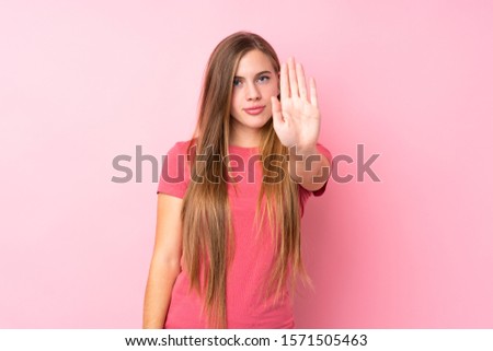 Teenager blonde girl over isolated pink background making stop gesture with her hand