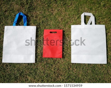 white and red Non Woven Colorful Bags on Green Grass, ECO Bags, Shopping Bags