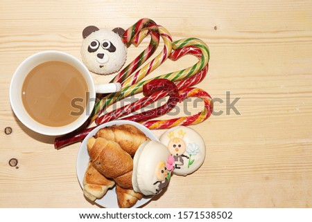 Cup of coffee with milk and fresh ruddy croissants, Christmas candies on a wooden table, top view, place for text. Concept of a modern bakery and christmas, rustic style. Tasty traditional breakfast.
