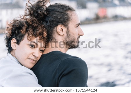 Stock photo of a girl hugging her partner in the back with the background sea out of focus. Lifestyle