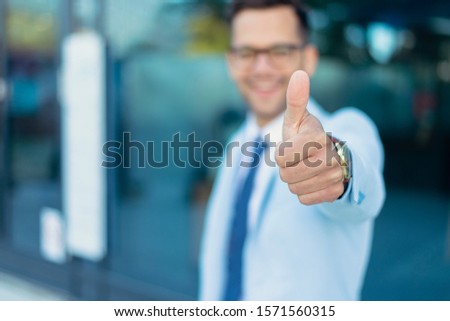 Young business man holding thumb up