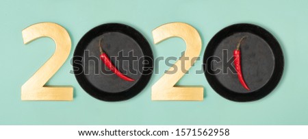 2020 eve top view new year number and pans with hot chillie pepperes as zero numbers. Flat lay style on neon mint background.