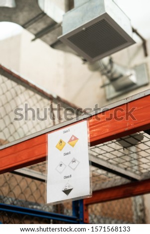 A vertical shot of danger signs on a red metal frame with a blurred background