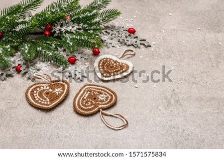 Christmas background. New Year fir tree, dog rose, fresh leaves, crocheted ginger cookies hearts and artificial snow. Stone concrete backdrop, copy space