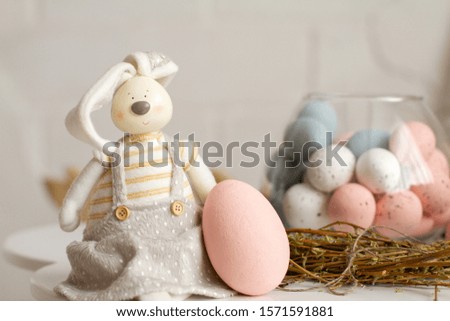 A rabbit is sitting at the Easter basket with colored eggs. Fluffy cute belly - a symbol of Easter. Religious holiday.
