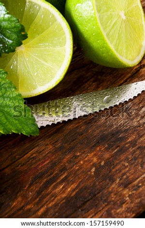 Limes and knife. On a wooden board.