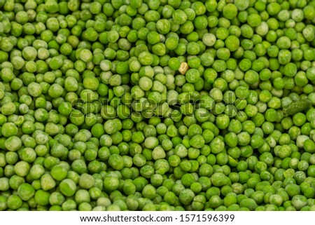 a lot of peeled green frozen peas. among it lies green beans.
 Royalty-Free Stock Photo #1571596399