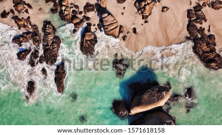 An overhead shot of the rocky coast of the sea with beautiful waves on a sunny day