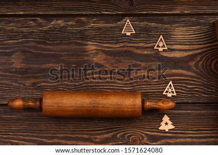 Christmas culinary layout on a wooden background. Wooden rolling pin with Christmas-tree elements for the menu of the festive table. Top view, flat style.