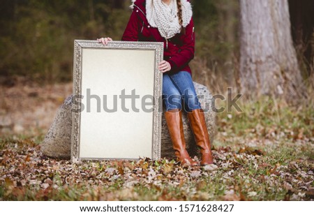 A selective shot of a person holding a blank picture frame as a space for your text