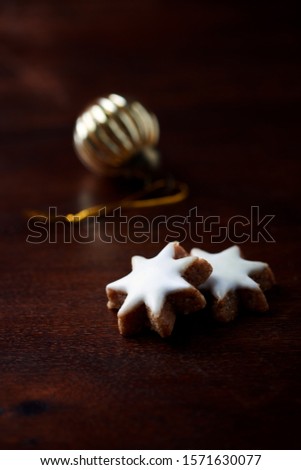 Christmas cookies (cinnamon stars) and Christmas golden bauble on dark background. Close up. 