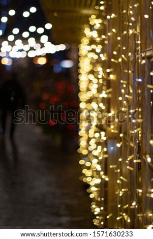 Festive Christmas illumination at night on the street. Bright golden yellow blurry lights. Christmas decor with luminous garlands with bright lights. Bokeh, blurry, texture